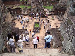 Tourists taking pictures at the khmer Pre Rup temple ruins, an example of cultural tourism.