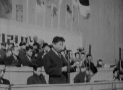 Kim Il Sung speaking at the first public celebration of the March First Movement in northern Korea in 1946.[169] A taegeukgi flag is flying above Kim; both the north and south used the design from 1945 to 1948.[170]