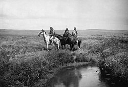 Three mounted Piegan chiefs on the prairie. Photographed by Edward S. Curtis.