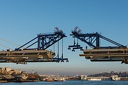 A bridge being constructed, with two large cranes on top