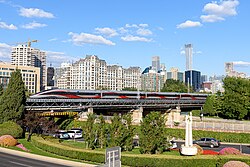 A train running on an elevated track through a commercial area