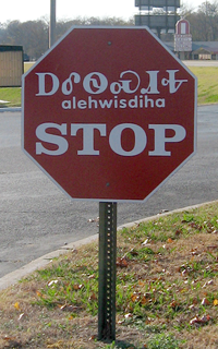A stop sign in Tahlequah, Oklahoma written in Cherokee using both the Cherokee syllabary (top) and Latin alphabet (middle), alongside English (bottom)