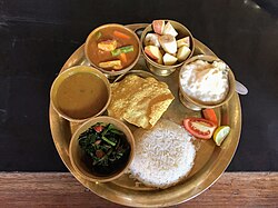 A dal-bhat thali with boiled rice, lentil soup, fried leafy greens, vegetable curry, yoghurt, papad and vegetable salad