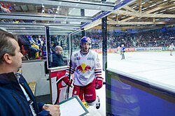 An ice hockey player enters the penalty box. Players may be sent to the penalty box for rule infractions, forcing their team to play with one less player for a specified time.