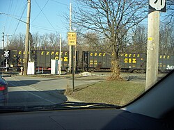The Coke Express rolls through a level crossing. Hopper cars display both the CSX logo and the words COKE EXPRESS.