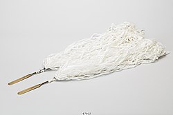 Two sticks with long white strings attached