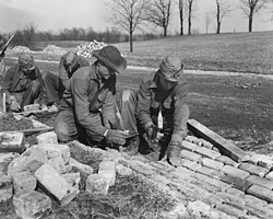 CCC workers constructing drainage culvert, 1933. Over 3 million unemployed young men were taken out of the cities and placed into 2,600+ work camps managed by the CCC.[213]