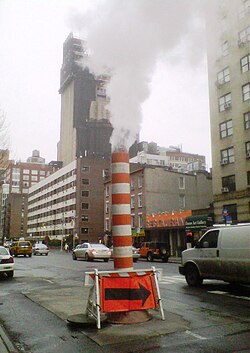 Steam vapor being vented through a typical Con Edison orange and white stack on Seventh Avenue at 20th Street