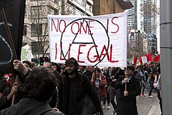 Pro-refugee protest in Melbourne, Australia, with a banner reading "No one is illegal" with a Circle A