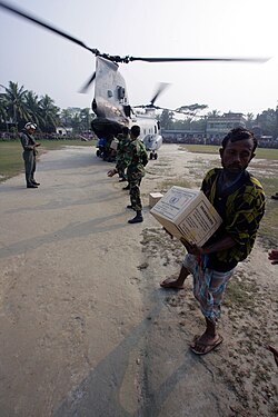 Bangladeshi citizens offload food rations from a US Marine CH-46E helicopter of 11th Marine Expeditionary Unit after Tropical Cyclone Sidr in 2007.
