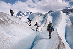A group of people scaling the glaciers by foot using crampons on their feet