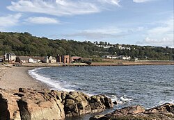 Wemyss Bay beach from rocks, railway in front of Kelly estate. Kelly House (once prominent in this view[6]) was located where modern "lodges" look out above houses on Shore Road.