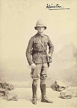 Winston Churchill posing in uniform in front of a backdrop depicting the Egyptian Pyramids, 1898.