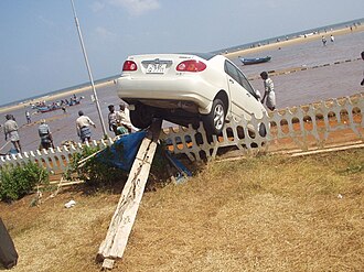 A Toyota Corolla deposited on top of a fence and various pieces of debris in Chennai