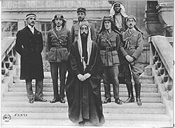 Emir Faisal's delegation at Versailles, during the Paris Peace Conference of 1919. Left to right: Rustum Haidar, Nuri as-Said, Prince Faisal, Captain Pisani (behind Faisal), T. E. Lawrence, unknown member of his delegation, Captain Tahsin Kadry.