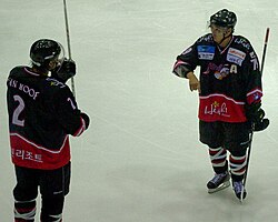 Alex Kim discusses strategy on-ice with Jeremy van Hoof. Kim won two points titles his first year in the league.