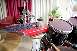 Triggers sensors in use, here they are red and mounted on the rims of the snare drum, bass drum and hanging toms. The larger box in the same color of red is the "brain" to which they are connected.