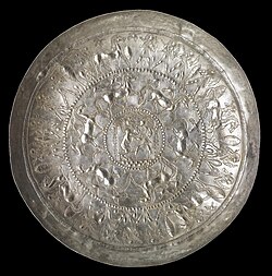 Phoenician metal bowl with hunting scene (8th century BC). The clothing and hairstyle of the figures are Egyptian. At the same time, the subject matter of the central scene conforms with the Mesopotamian theme of combat between man and beast. Phoenician artisans frequently adapted the styles of neighboring cultures.