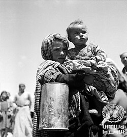 A Palestine refugee girl and her baby brother wait shyly for their daily ration of food and milk from the UNICEF