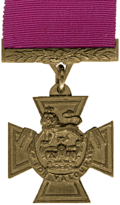 A bronze cross pattée bearing the crown of Saint Edward surmounted by a lion with the inscription 'FOR VALOUR'. A crimson ribbon is attached.