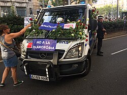 A woman leaves flowers in a Guàrdia Urbana van after the attack