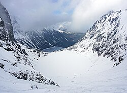 Higher Czarny Staw pod Rysami lake (elevation 1,583 metres (5,194 ft)) is still frozen as the lower Morskie Oko lake has already almost melted (elevation 1,395 metres (4,577 ft)). Photo from Polish side of the Tatra mountains, May 2019.