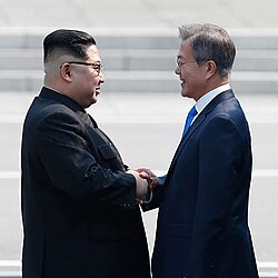 Moon and Kim shaking hands over the demarcation line