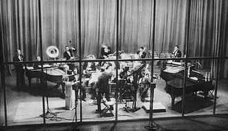 Rudy Vallée conducts his orchestra while guest star Frances Williams sings in 1933