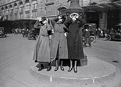 Three Parisian women watching the solar eclipse of 8 April 1921 through glasses on the Cour du Havre, next to the gare Saint-Lazare.