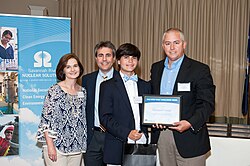 A young man (in a bowtie) receives a scholarship at a ceremony.