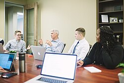 A woman and three men sitting in a conference meeting