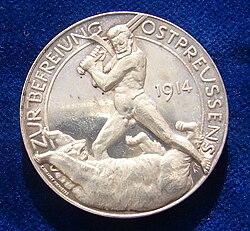 The reverse of a World War I German Silver medallion liberation of East Prussia 1914 by Paul von Beneckendorff und von Hindenburg. Referring to the Battle of Tannenberg. The naked Gen. Hindenburg fighting the Russian Bear with his sword.