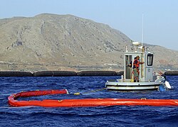 A US Navy oil spill response team drills with a "Harbour Buster high-speed oil containment system".