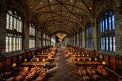 The interior of the reading room of the library, with tables and lamps on either side of the hall