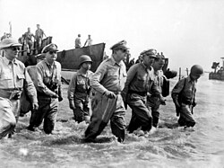 A group of men wading ashore. With General MacArthur is Philippine President Sergio Osmeña and other U.S. and Philippine generals.