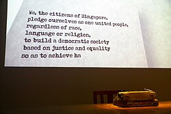 An animated display at the National Museum of Singapore featuring a portion of the National Pledge. The remainder of the Pledge, which does not appear in the photograph, is "... so as to achieve happiness, prosperity and progress for our nation".