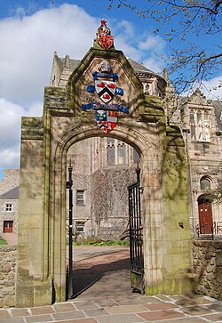 This archway, designed by AM Mackenzie, leading to the forecourt of the New King's Building at King's College portrays, from top to bottom, the coat of arms of Scotland, the coat of arms of Bishop Elphinstone, and the university's coat of arms. It is also engraved with the university's Latin motto, Initium Sapientiae Timor Domini.