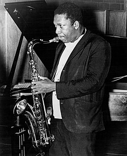 Man in a dark suit playing a saxophone