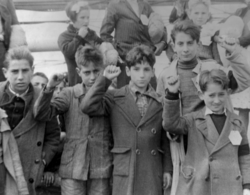 Children preparing for evacuation, some giving the Republican salute. The Republicans showed a raised fist whereas the Nationalists gave the Roman salute.[note 4]