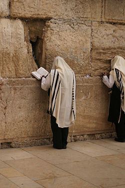 Men wearing tallitot pray at the Western Wall